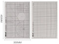 Green A3 self-healing cutting mat with centimetre grid lines on a wooden desk.