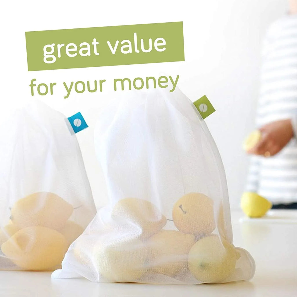 Five white cotton drawstring bags for kitchen vegetable storage arranged on a clean surface