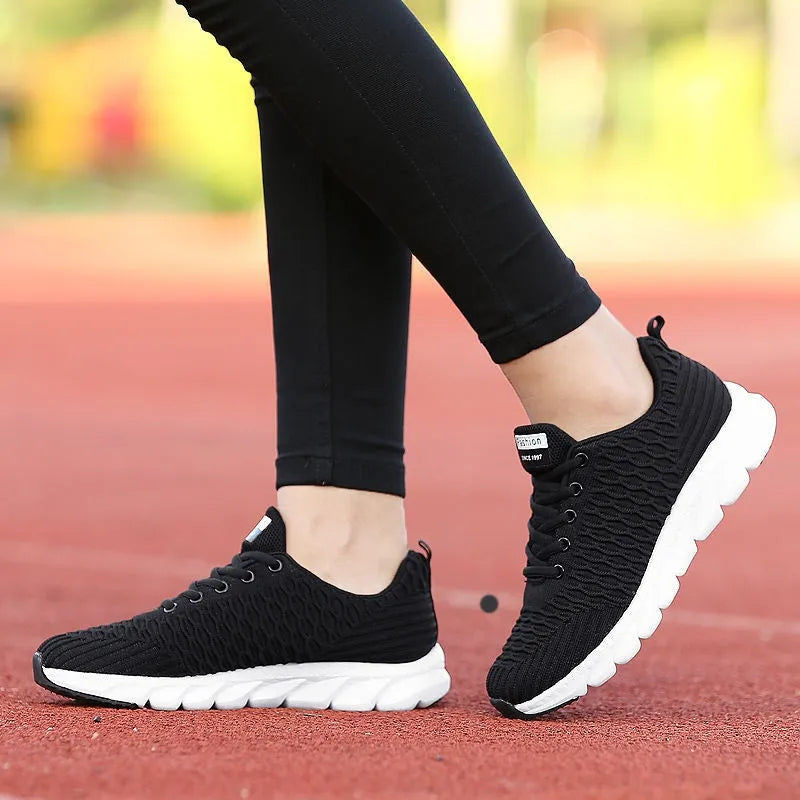 Women's running shoes in black, pink, or white with fly weave upper and durable outsole.