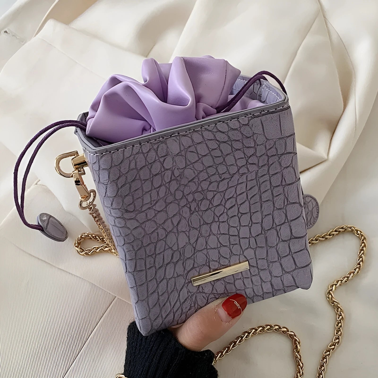 Small green women's bucket bag with a metal chain strap, shown worn cross-body, with zip open revealing interior ID pocket.