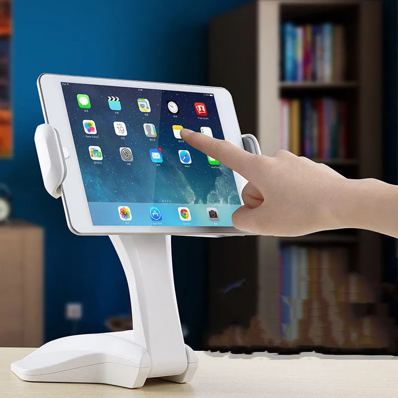 White aluminium tablet stand on a desk, showing its height and the adjustable clip for 7-15 inch devices.