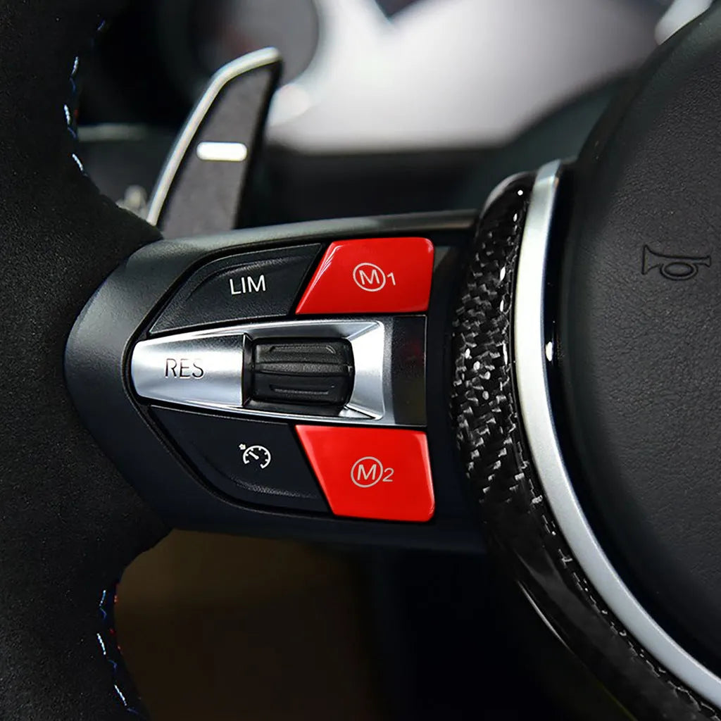 Pair of red and blue BMW M1 and M2 steering wheel mode buttons on a white background.