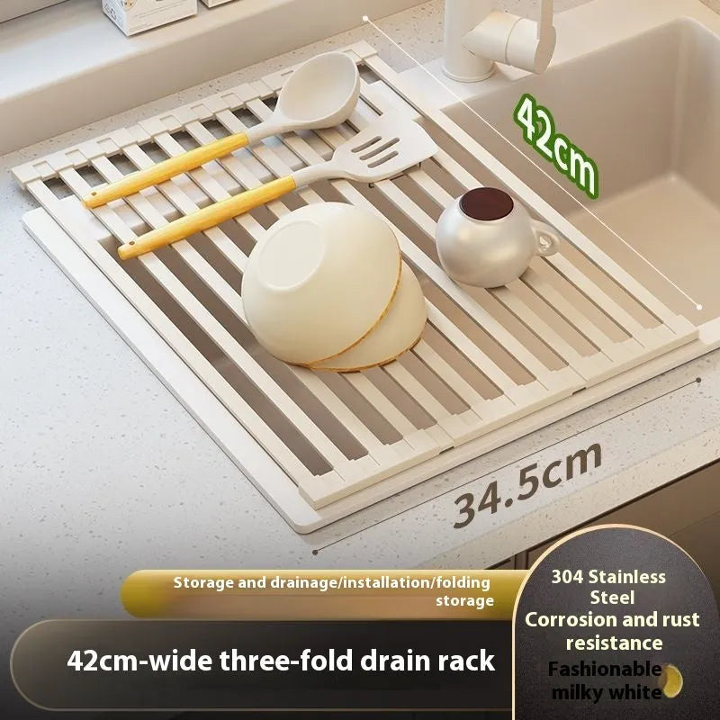 Milky White foldable stainless steel kitchen draining rack shown beside a sink, demonstrating its tri-fold mechanism.