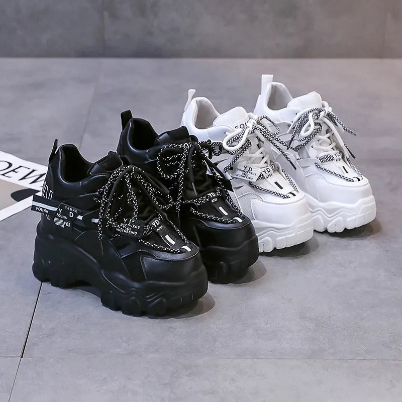 Women's white and black platform sports shoes with cross strap and rubber sole.