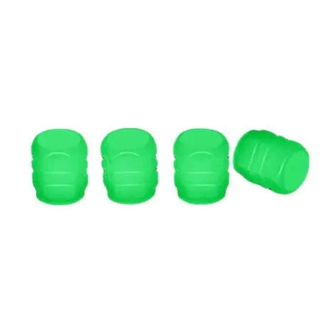 Set of four glowing green LED tyre valve caps screwed onto a car wheel valve stems at night.