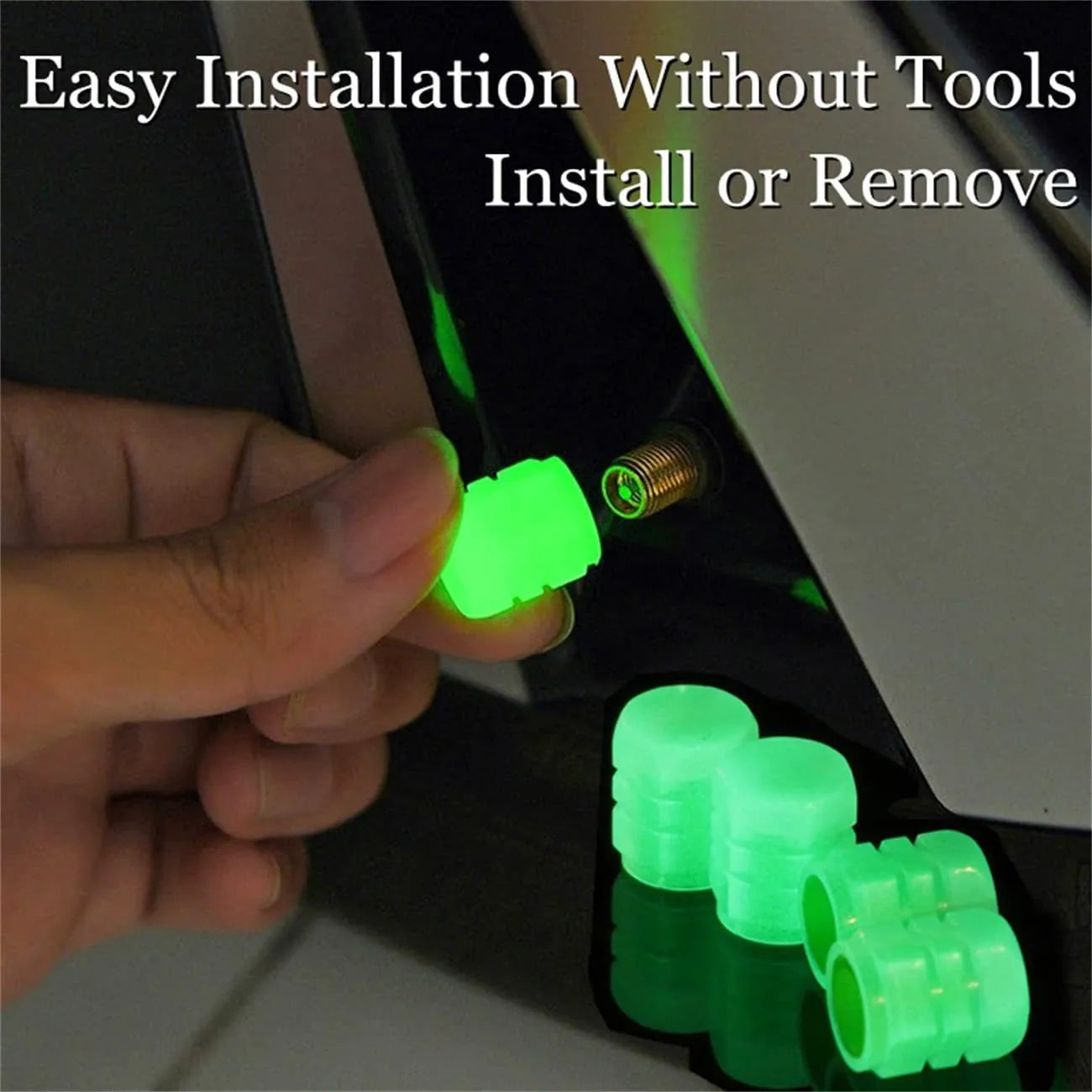 Set of four glowing green LED tyre valve caps screwed onto a car wheel valve stems at night.