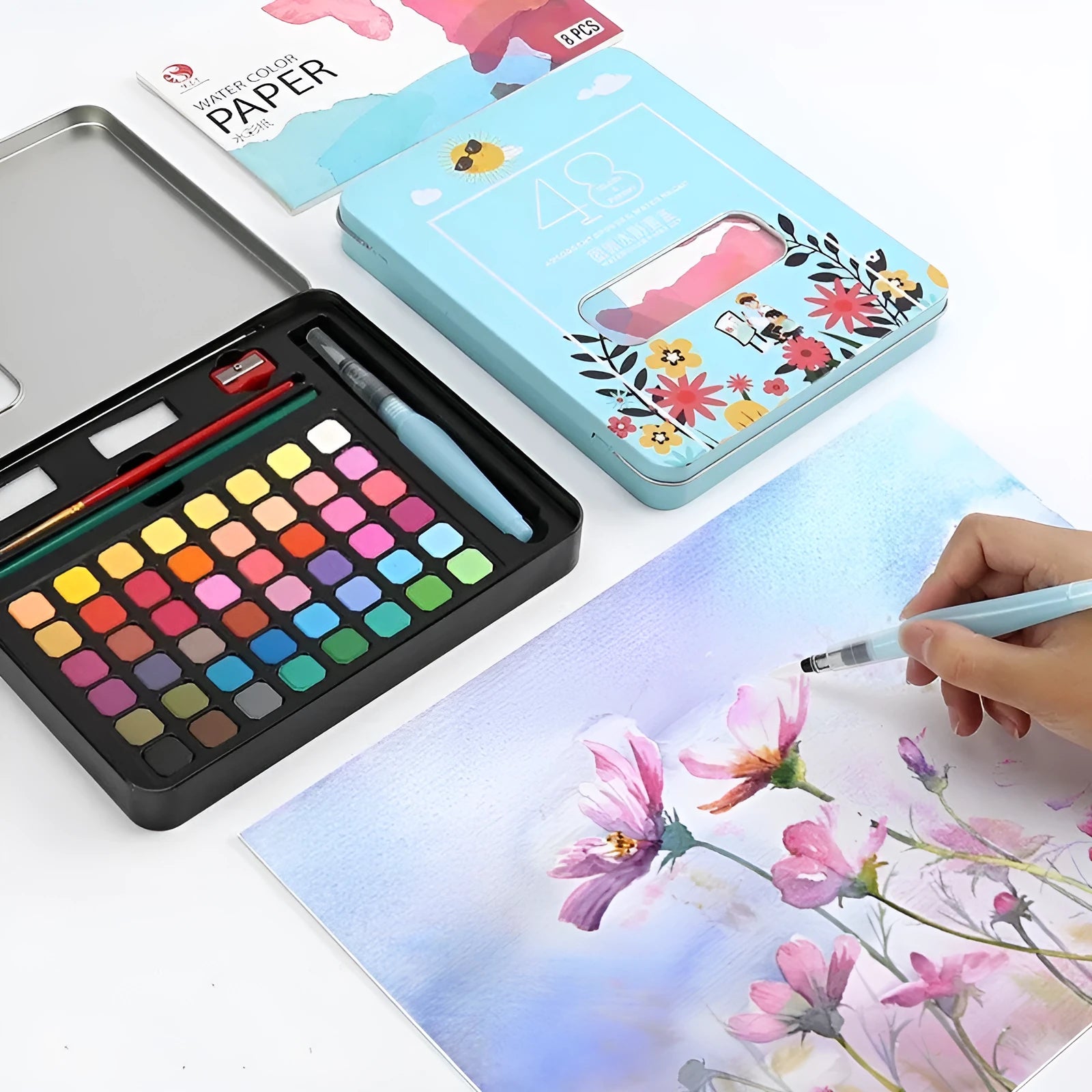 Box containing 48 solid watercolour paint cakes in various colours including black, pink, and blue.