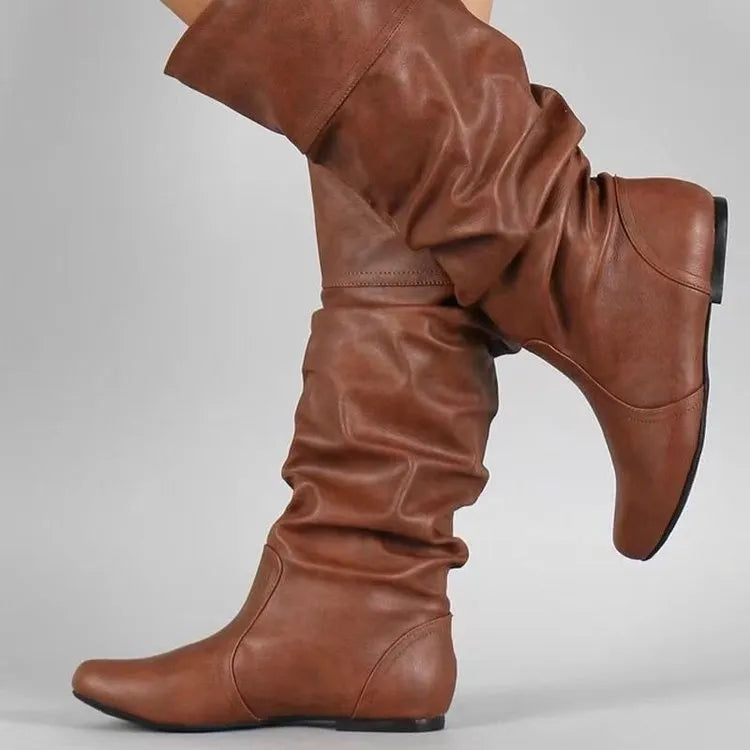 Women's flat black slip-on boots with a round toe and high cylinder shaft on a neutral background.