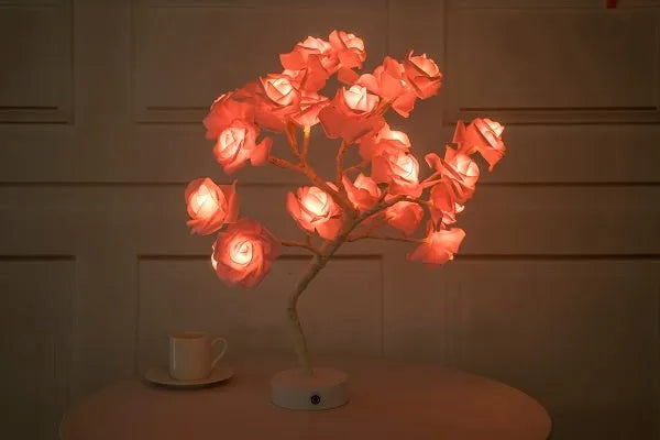 White and red rose flower LED table lamp with bonsai tree garland on a wooden table.