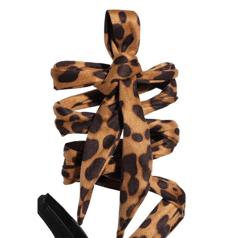 Light brown leopard print women's high heels with criss-cross ankle straps and a slim 8cm stiletto heel on a rubber sole.