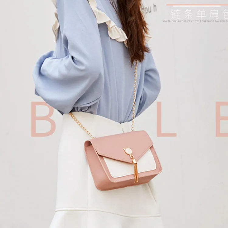 Small square PU leather messenger bag with cat tassel decoration and chain strap on a white background