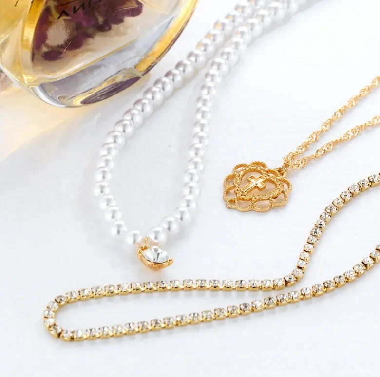 Gold multi-layer rhinestone and imitation pearl necklace on a white background