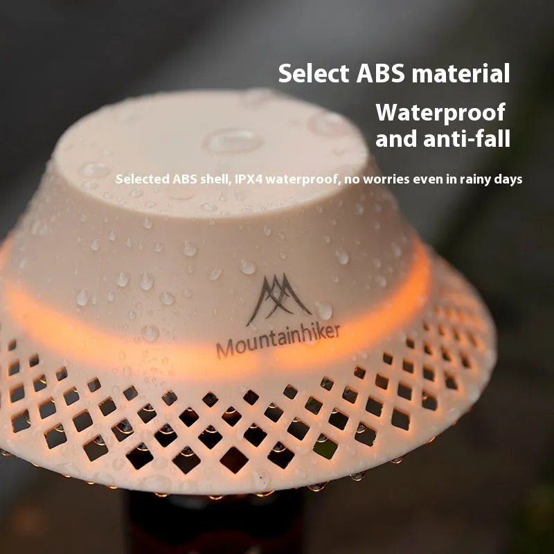 Beige wine bottle-shaped camping lantern with LED light on a wooden surface outdoors.