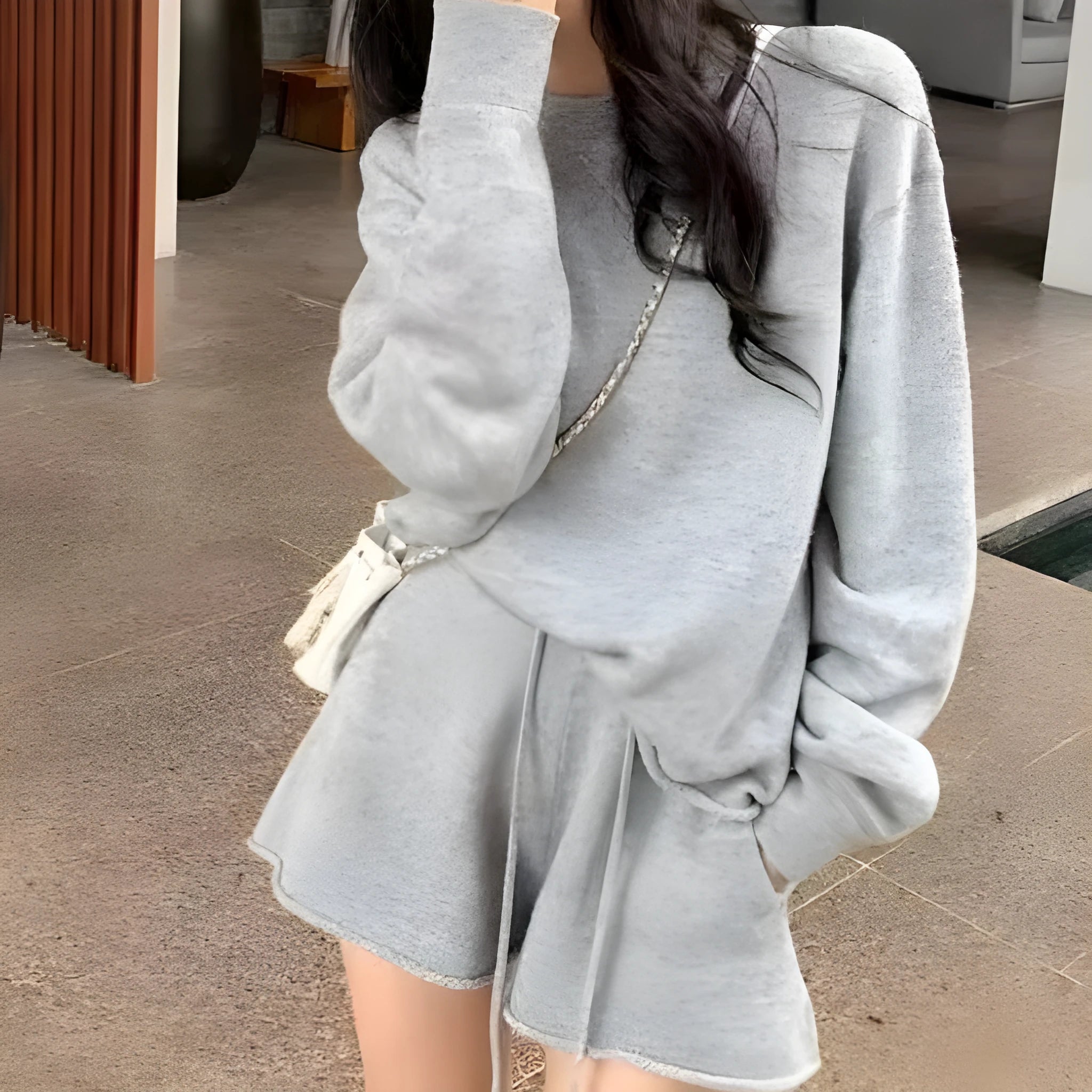 Woman wearing a loose beige knitted sweater and matching wide-leg shorts, a loungewear set on a neutral background.