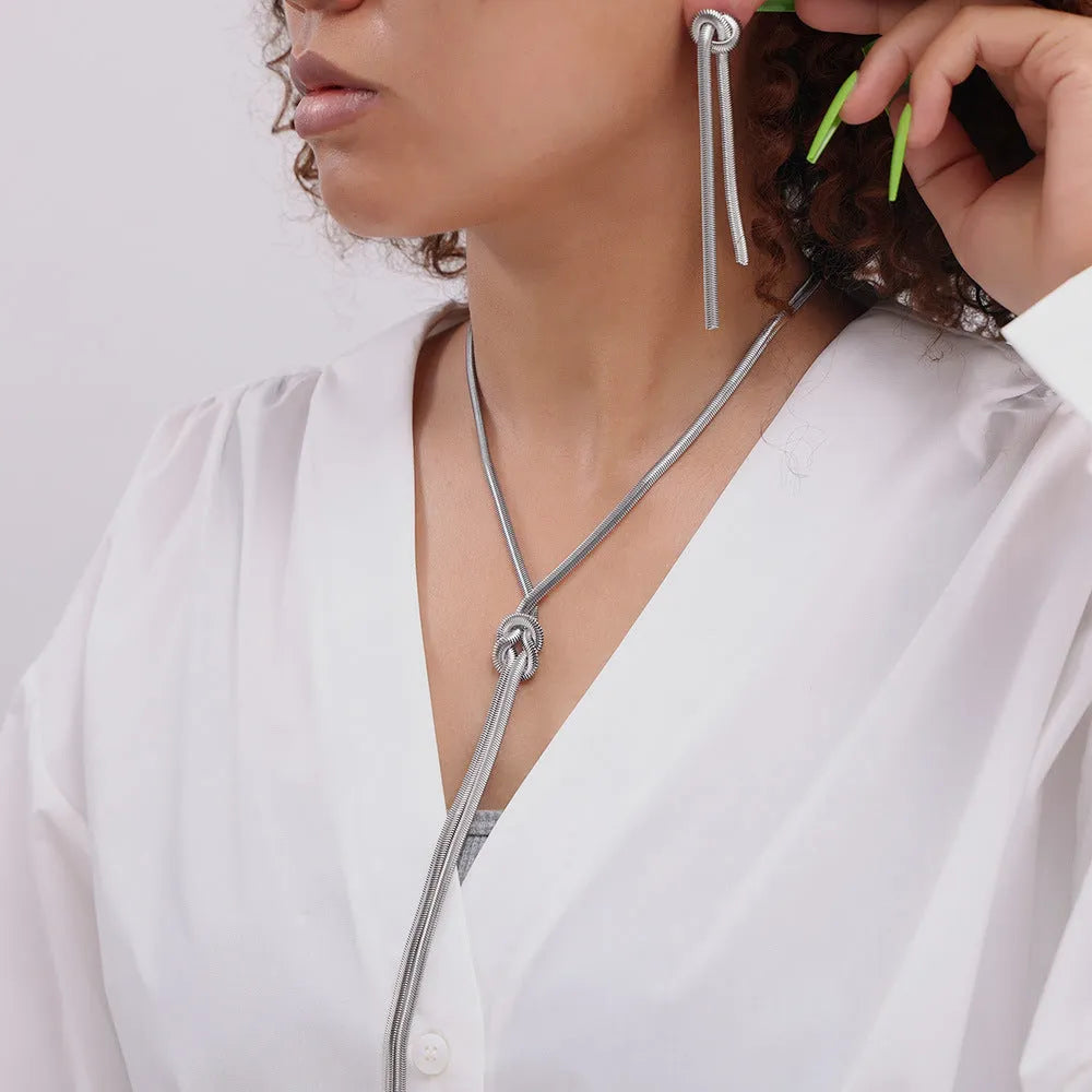 Gold titanium steel knotted tassel necklace and matching earrings set on white background