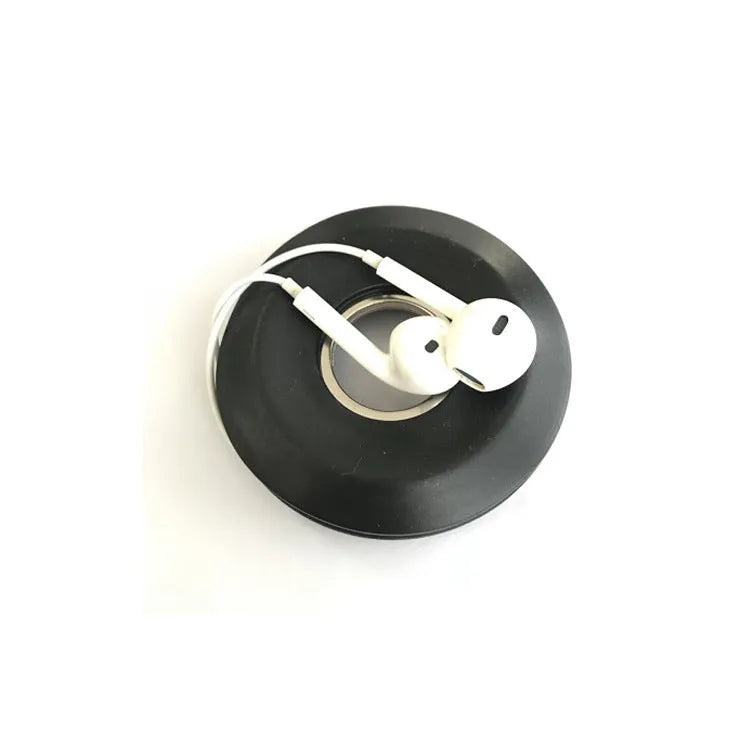 Light grey silicone donut cord reel with suction cup base and magnet for organising phone and earphone cables.