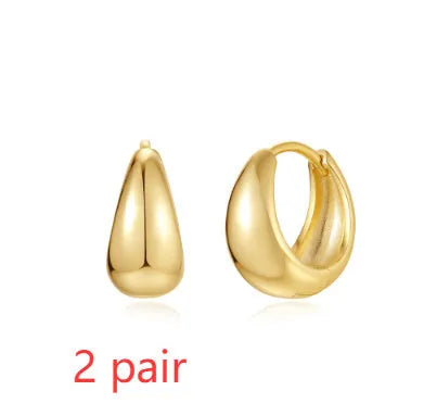 A pair of geometric brass earclip earrings with round diamond details on a gold electroplated copper base.