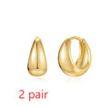 A pair of geometric brass earclip earrings with round diamond details on a gold electroplated copper base.