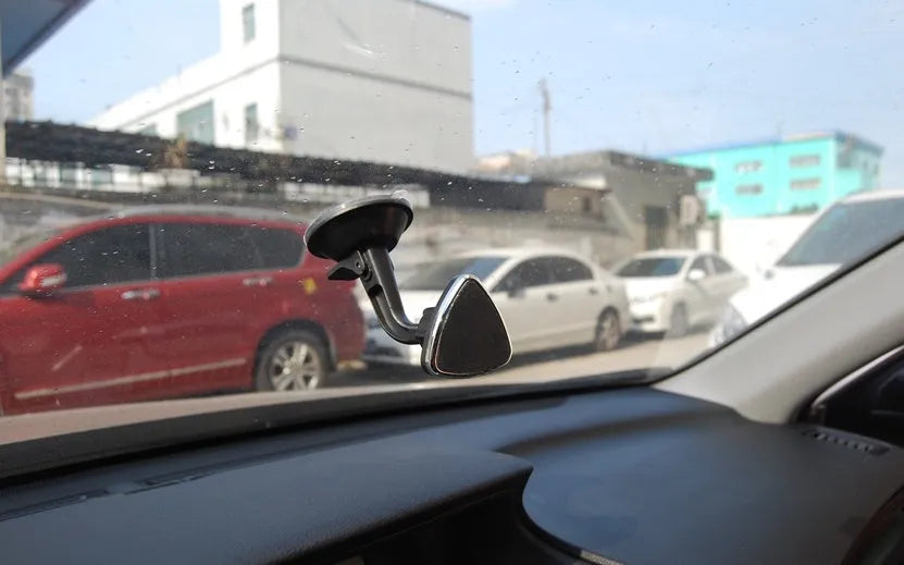 Black magnetic car phone holder mounted on dashboard with smartphone attached showing 360-degree rotation feature
