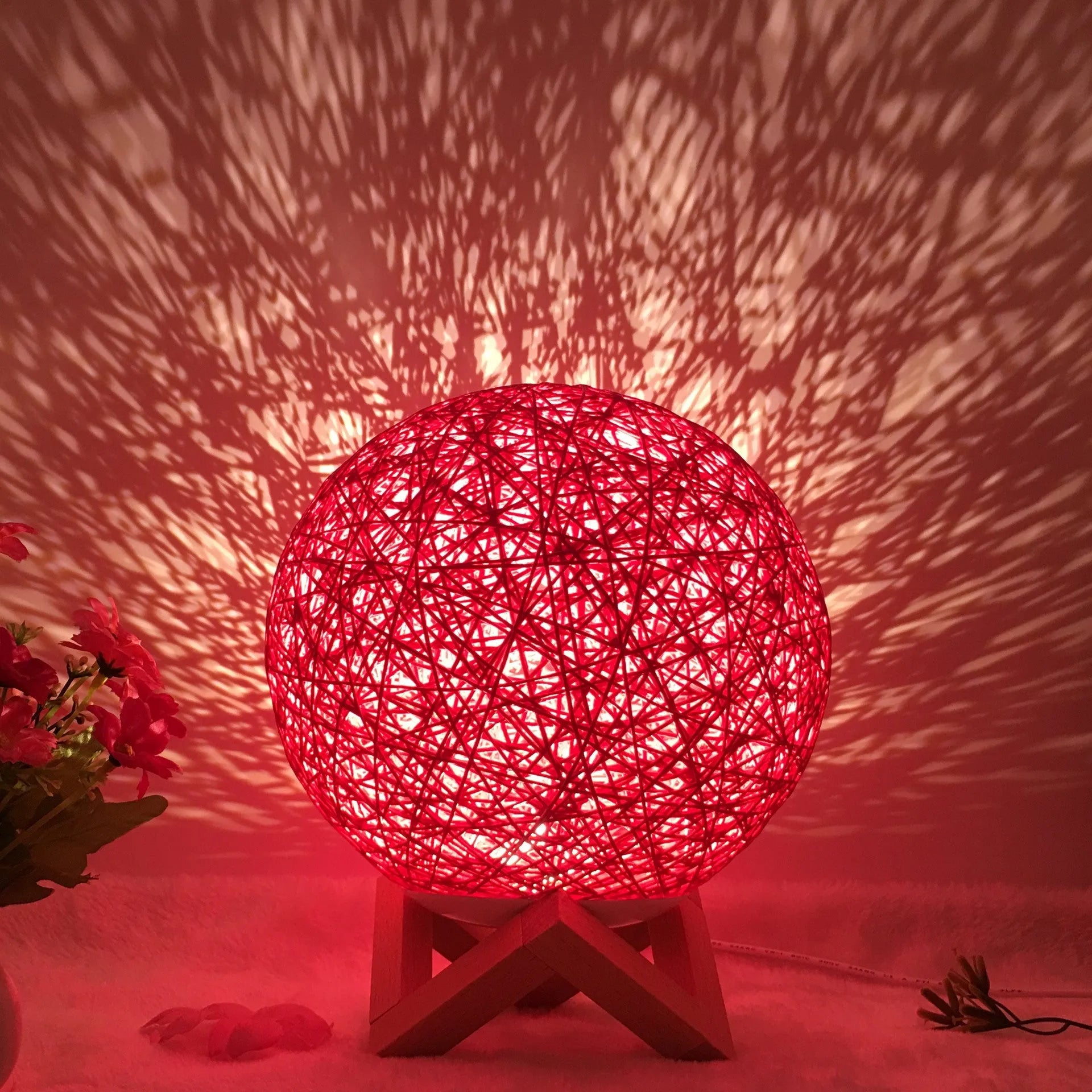 Rattan ball table lamp with woven shade and warm LED lighting on wooden surface