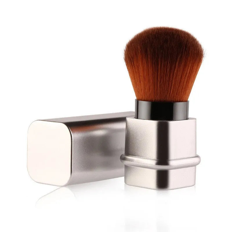 Portable single makeup brush with man-made fibre bristles and square gold plastic handle on white background