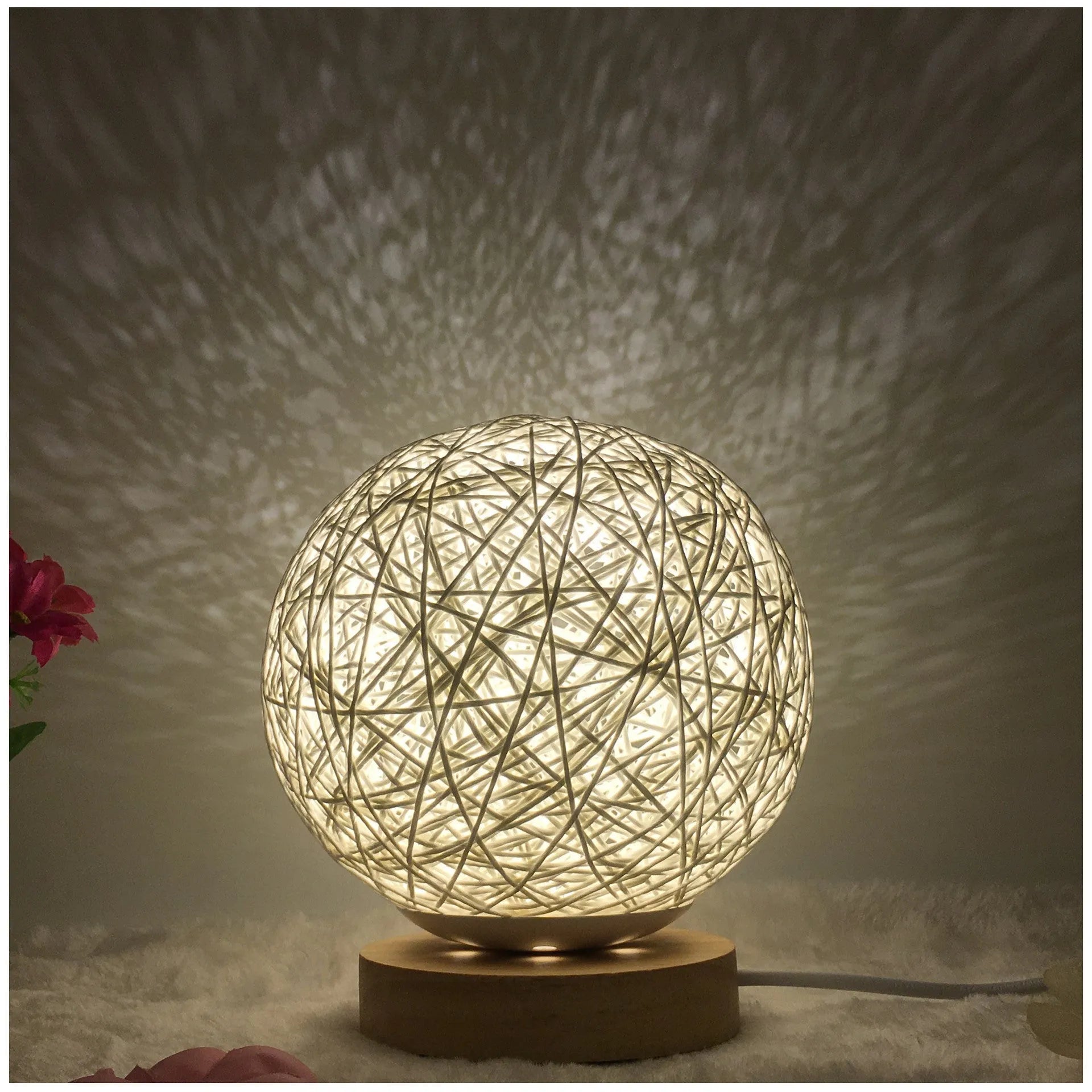 Rattan ball table lamp with woven shade and warm LED lighting on wooden surface