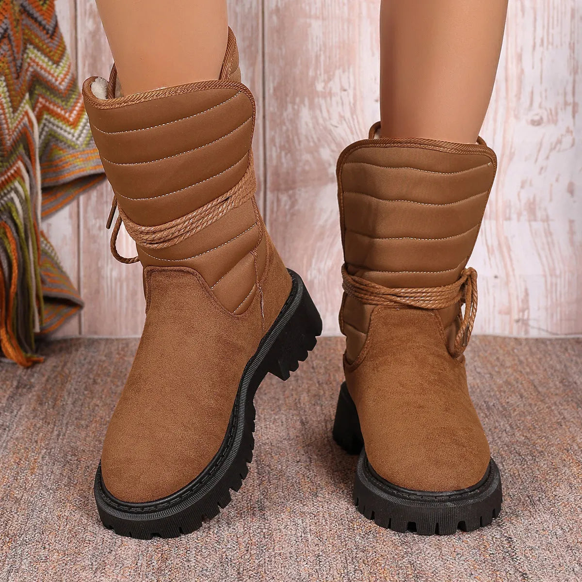 A pair of women's chunky heel snow boots in suede with a lace-up front and fleece lining, shown in black.