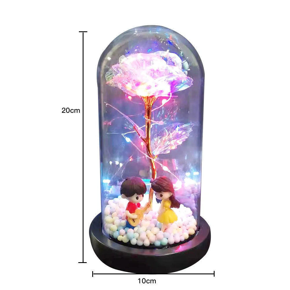 Artificial gold rose in clear glass dome on black base with LED lights for home decor