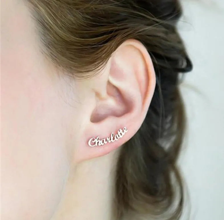 Custom English letter name earrings in rose golden finish on a plain background