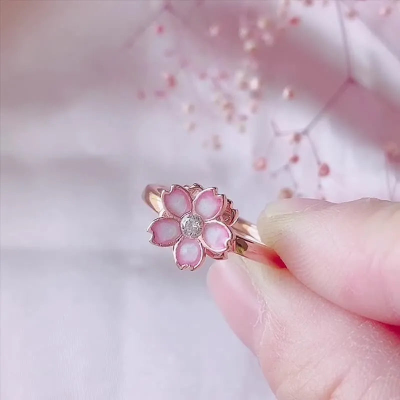 Cherry blossom rotatable ring with rose gold finish, adjustable opening, and silver base shown on a finger