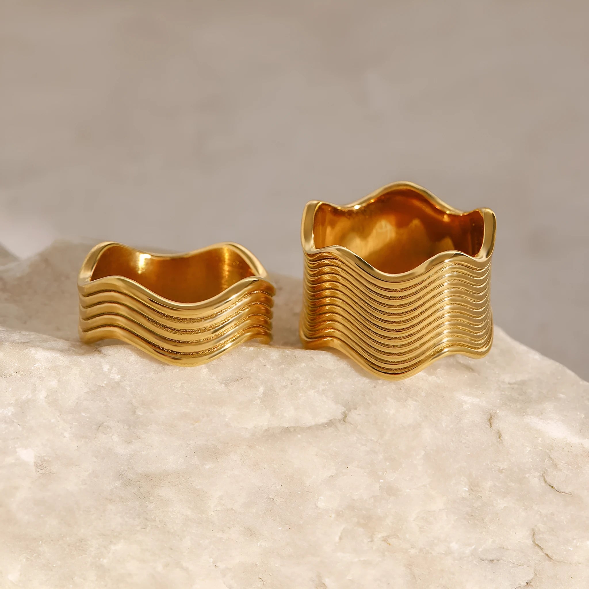 Stainless steel wide band wave ring in geometric Korean style on a plain background.