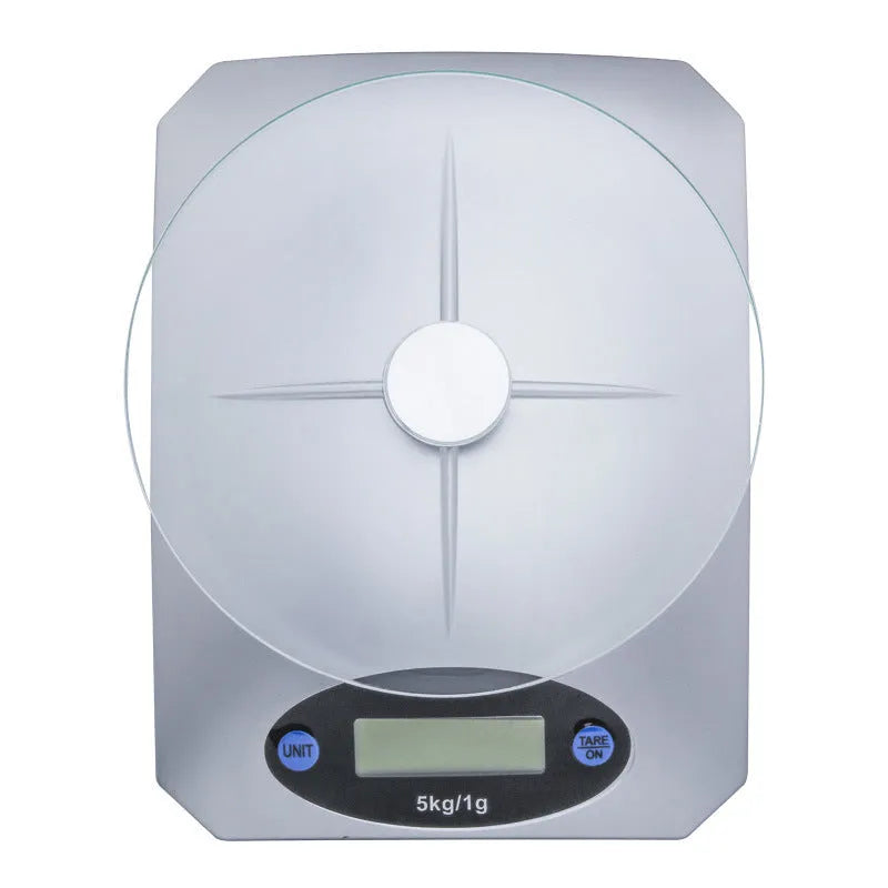 Simple mini kitchen electronic scale in silver white colour on a flat surface, showing weighing display.