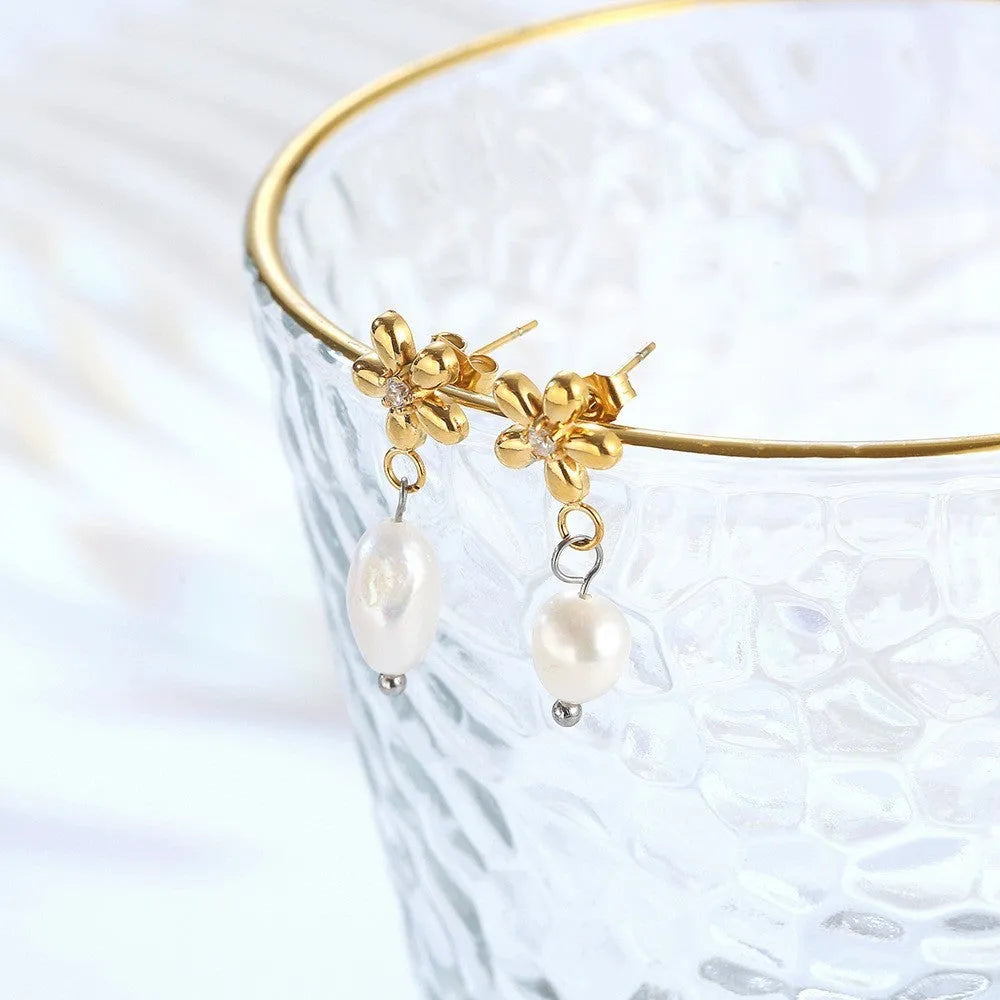 Women's gold titanium steel C-shaped earrings with pearl inlay flower design on white background