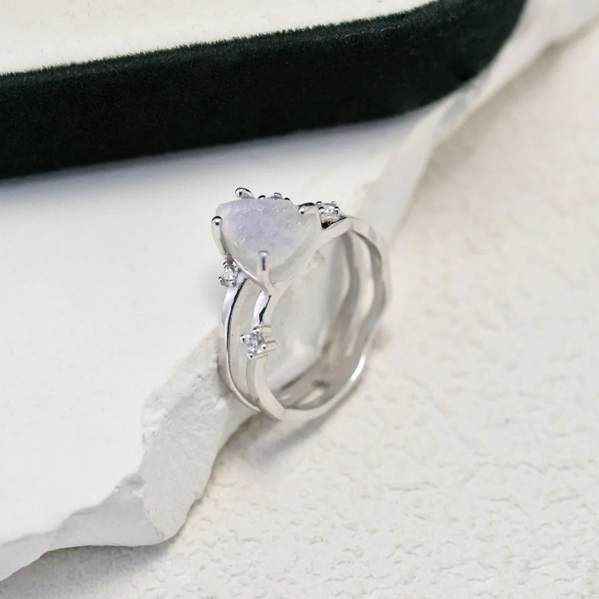 S925 silver geometric ring with irregular triangle shape and moonstone on a model's hand.