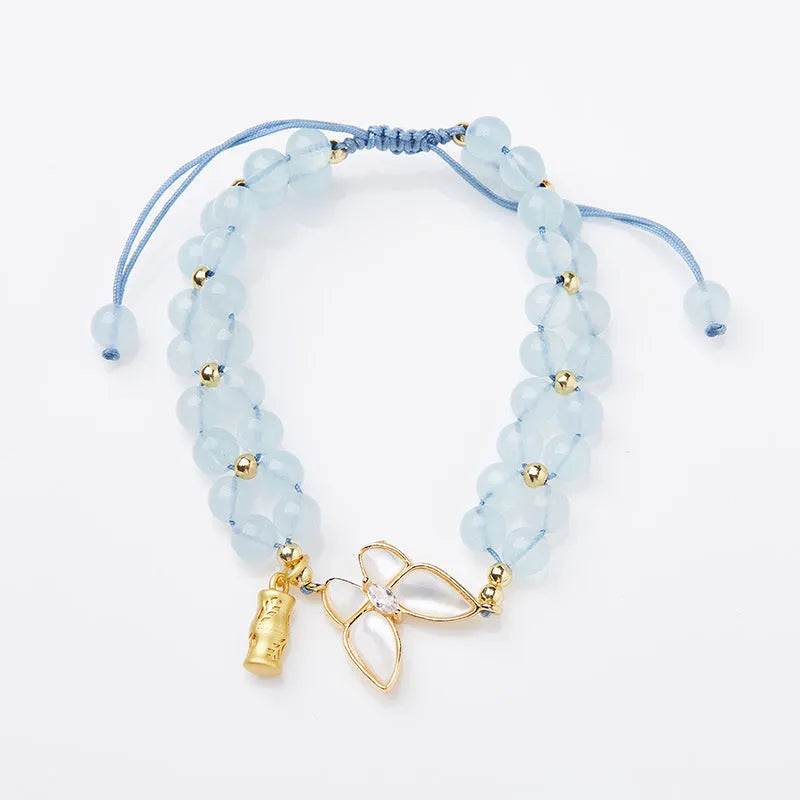 Close-up of a handmade women's woven bracelet with 6mm butterfly design in aquamarine gemstone beads.