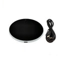 Black USB heating coaster with tempered glass plate on a desk next to a coffee mug