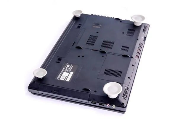 Set of four grey plastic laptop cooling pads with non-slip rubber feet, shown elevating a silver laptop.