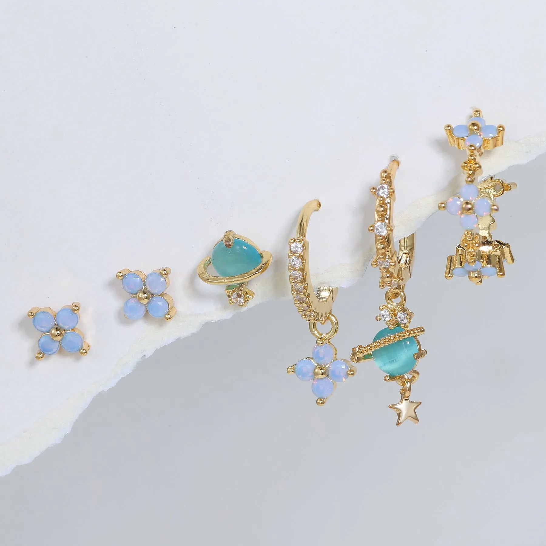 Gold and silver flower-shaped ear studs with zircon mosaic detail on a white background.