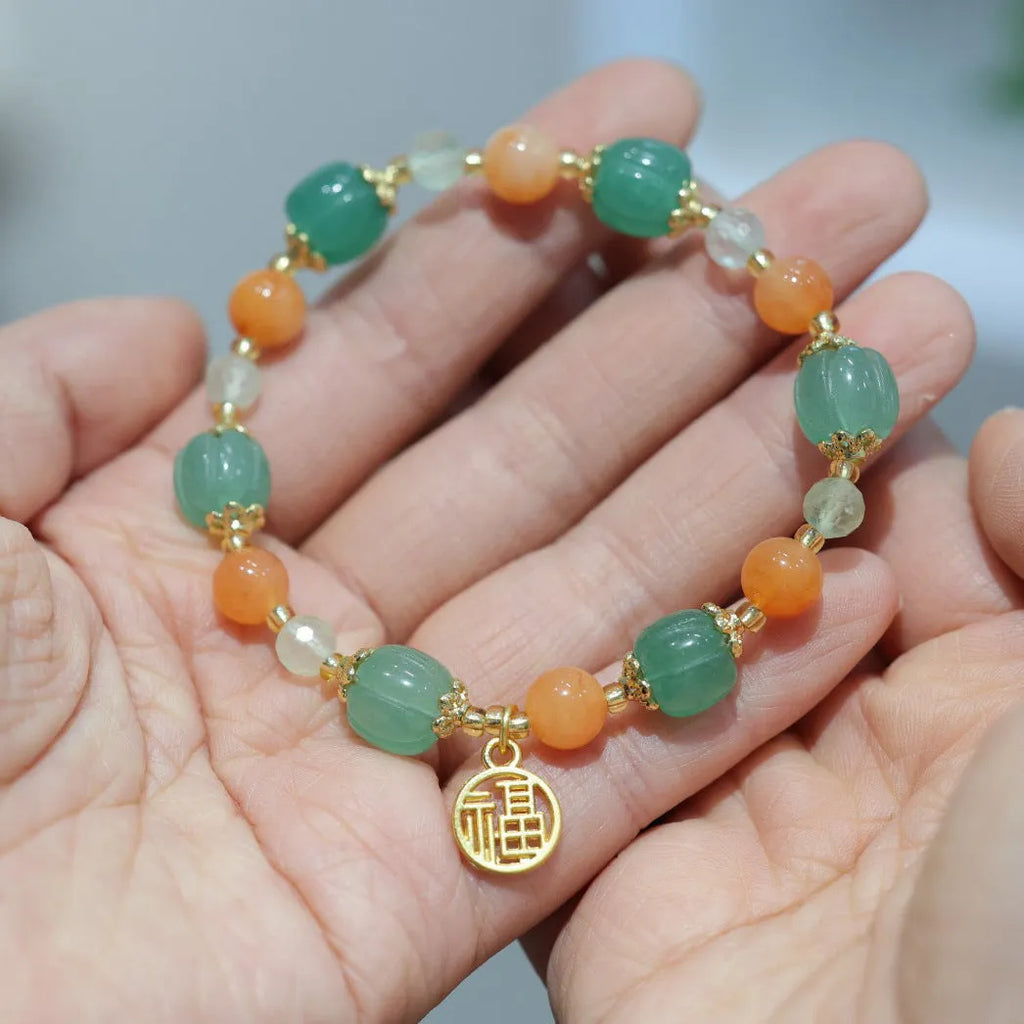 Close-up of a jade and prehnite Chinese-style pumpkin bead bracelet on a wrist.