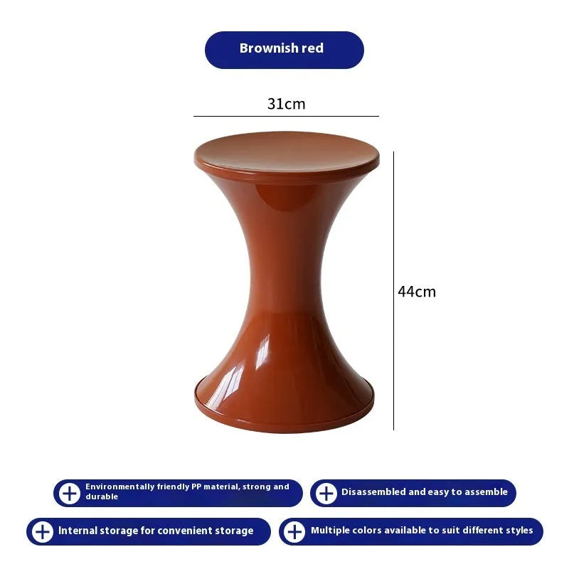Green plastic hourglass-shaped shoe changing stool on a wooden floor.