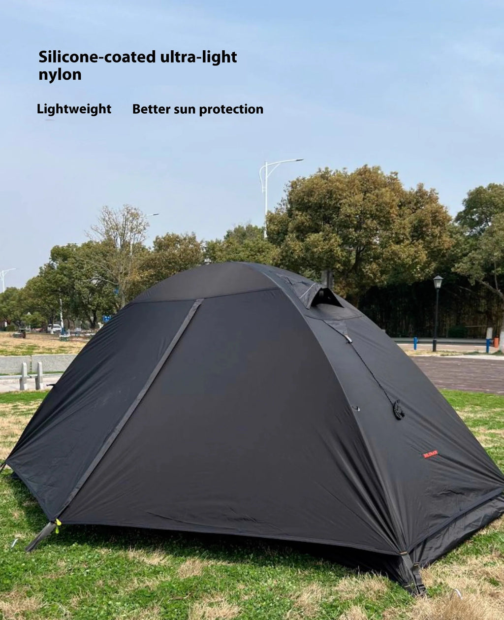 Single person hiking tent in orange pitched in a forest, showing aluminium poles and double-layer design with mesh panel.