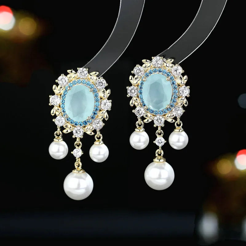 Pair of oval copper earrings with inlaid zircon and a white pearl tassel drop.