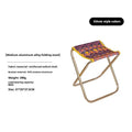 Black ethnic style aluminium alloy folding camping stool shown in use outdoors.
