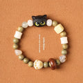 Hand-woven beaded bracelet with bodhi, jade, and ebony beads featuring a cartoon cat's paw charm.