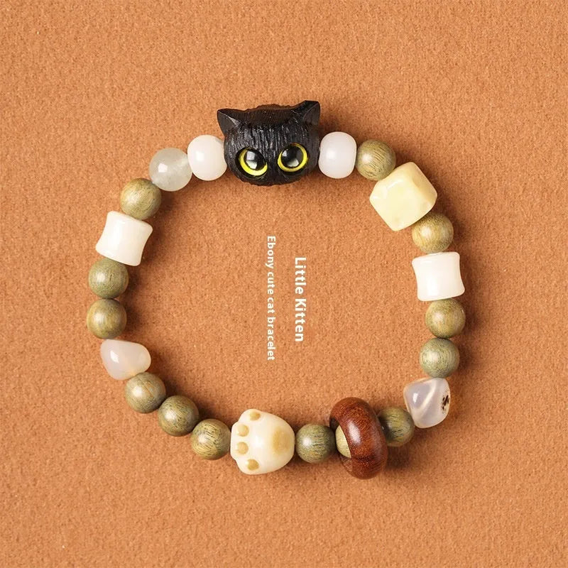 Hand-woven beaded bracelet with bodhi, jade, and ebony beads featuring a cartoon cat's paw charm.
