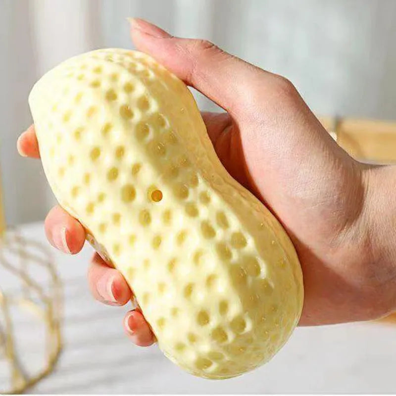 Yellow TPR peanut-shaped dog chew toy with textured shell on a white background.