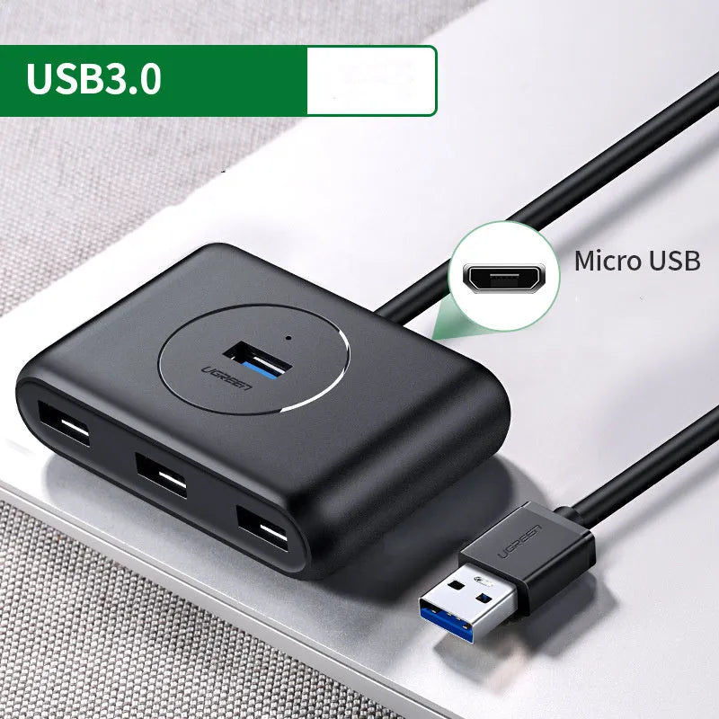 Deep black USB splitter with four ports, Micro USB power port, and indicator light on a desk