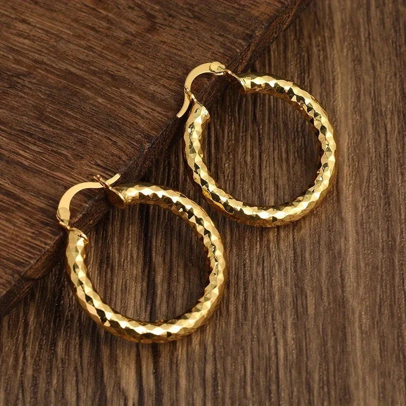 Pair of gold-coloured retro classic alloy earrings for women on a neutral background
