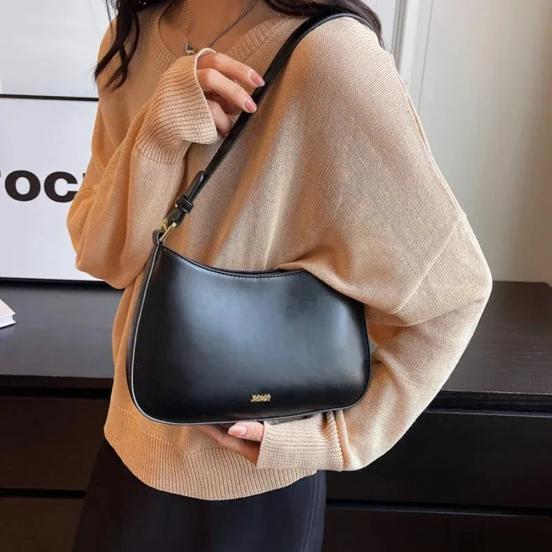 Red underarm shoulder bag in textured faux leather with adjustable strap for crossbody or sling wear