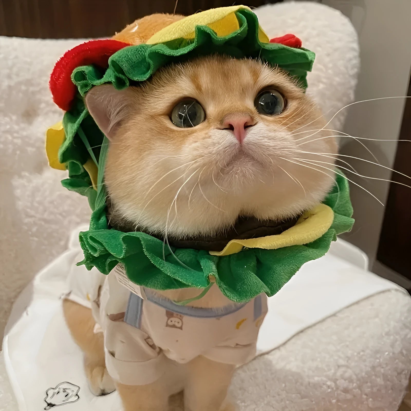 A soft burger bun headdress with a felt cheese slice for cats, shown with an adjustable neck strap.